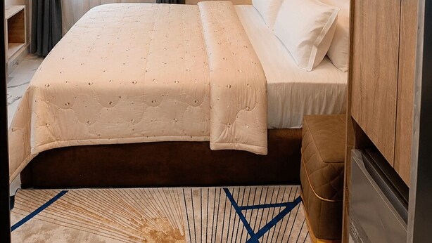 Una habitación de hotel con cama, un cuadro, un armario y un equipo de aire acondicionado.