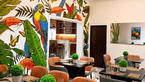 Un comedor con un mural tropical, muebles modernos y un diseño de techo contemporáneo.
