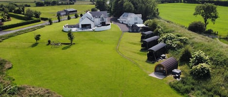 A rural property with a large lawn, several buildings, and a road.