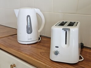Un plan de travail de cuisine avec une bouilloire électrique blanche et un grille-pain blanc.