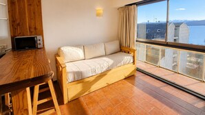 A room with a wooden sofa, a small table, and a view of a body of water through large windows. - Lake and City steps from the Centro Civicoc (San Carlos de Bariloche)