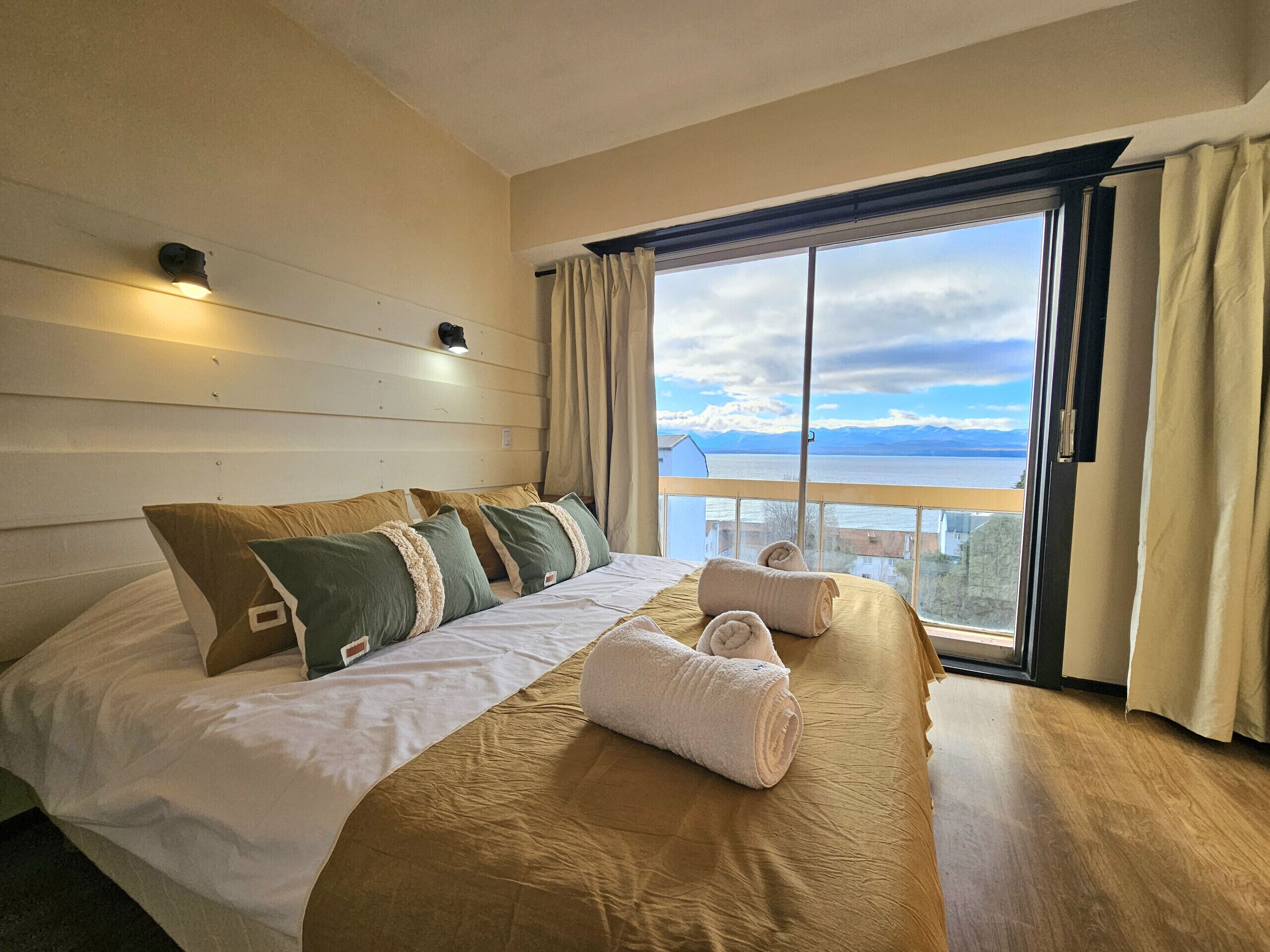 A hotel room with a bed, a view of the sea, and a balcony.