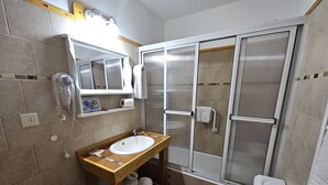 A bathroom with a wooden vanity, a white sink, a toilet, and a glass-enclosed shower. - Lake and City steps from the Centro Civicoc (San Carlos de Bariloche)