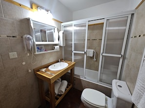 A bathroom with a wooden vanity, a white sink, a toilet, and a glass-enclosed shower. - Lake and City steps from the Centro Civicoc (San Carlos de Bariloche)