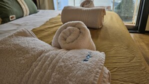A hotel room with a bed, two rolled towels, a view of mountains through a window, and a balcony. - Lake and City steps from the Centro Civicoc (San Carlos de Bariloche)