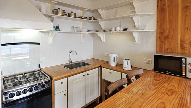 A compact kitchen with white cabinetry, a gas stove, a microwave, and a wooden countertop. - Lake and City steps from the Centro Civicoc (San Carlos de Bariloche)