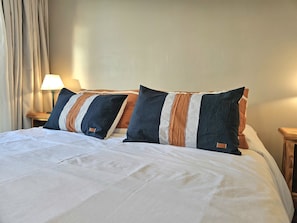 Ein ordentlich bezogenes Bett mit weißer Bettdecke und zwei Kissen mit Streifenmuster.
