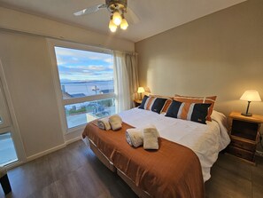 Ein Hotelzimmer mit einem großen Bett, zwei Nachttischlampen, einem Deckenventilator und einem Fenster mit Blick.