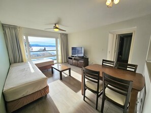A hotel room with a bed, a desk, a dining table with chairs, a television, and a view of the outdoors. - Araucaria with LAKE views and parking (San Carlos de Bariloche)