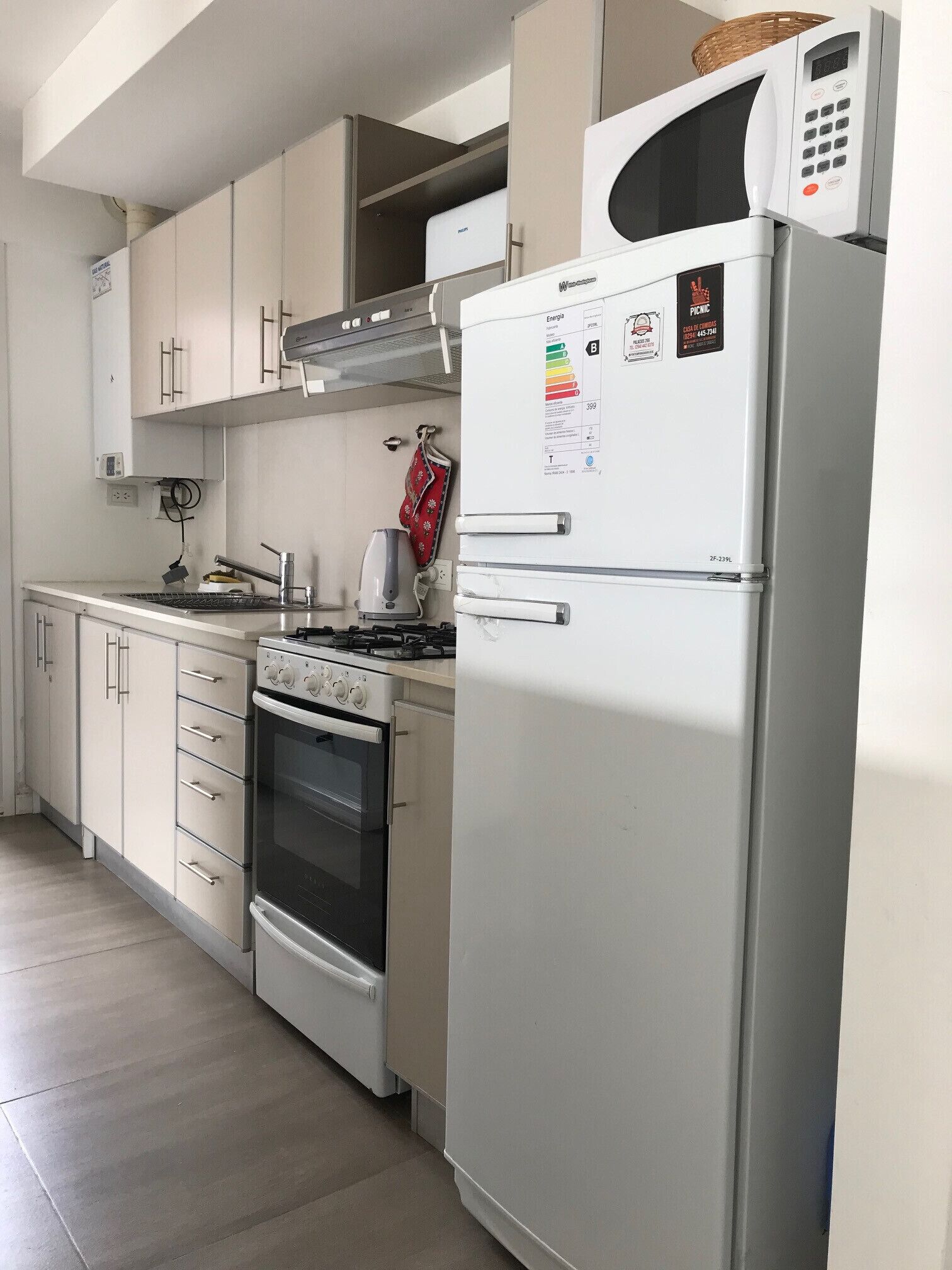 A kitchen with a built-in stove, oven, and a refrigerator with a microwave on top.