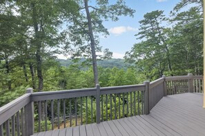 Eine Holzterrasse mit Geländer, mit Blick auf ein bewaldetes Gebiet.