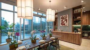 A modern dining area with a long table, chairs, and potted orchids. - Student Only Square Gardens Acer (Manchester)