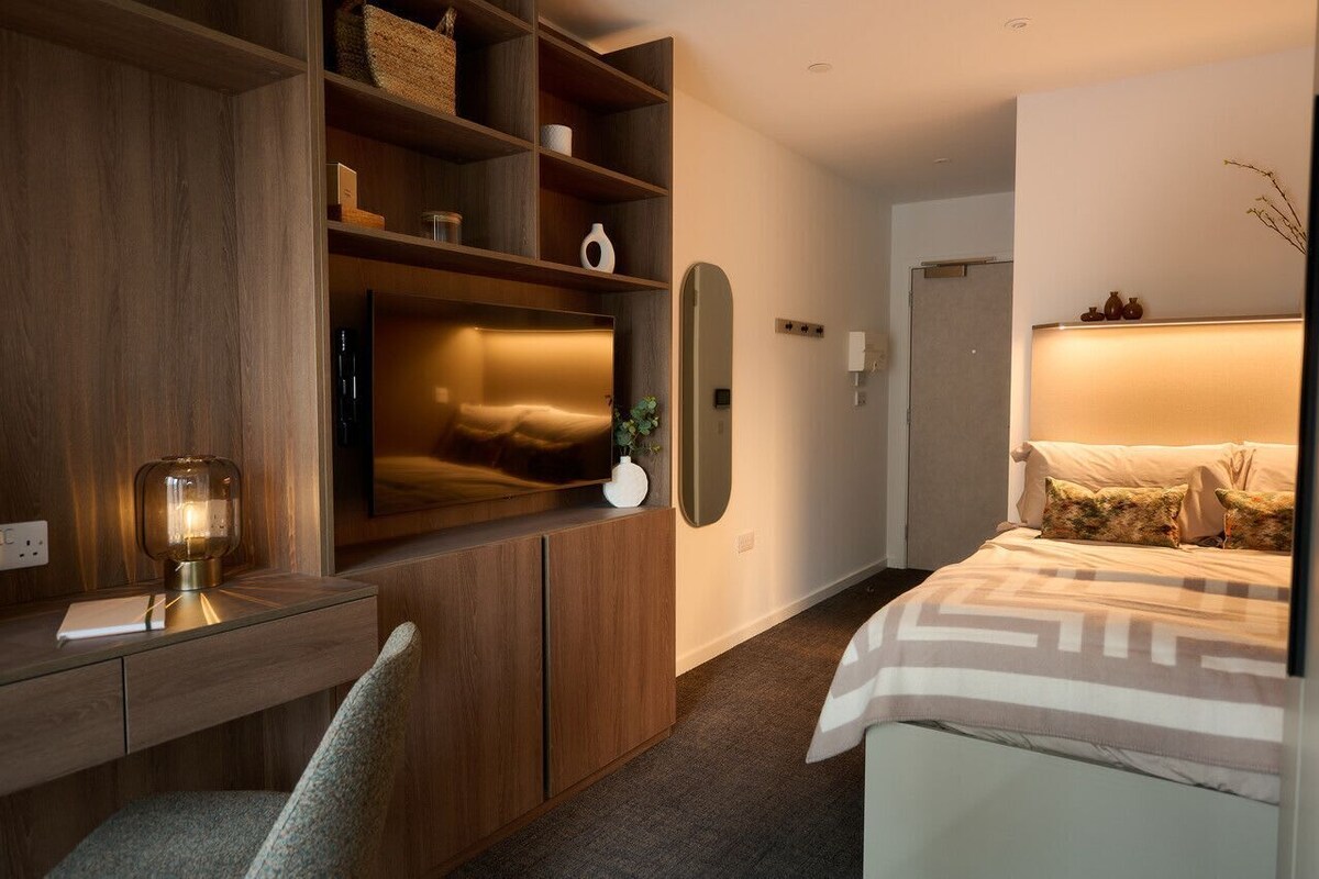 Ein modernes Schlafzimmer mit Bett, Schreibtisch mit Lampe und Einbauschränken.