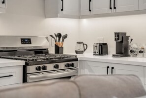 Eine moderne Küche mit Gasherd, Kaffeemaschine und Wasserkocher.