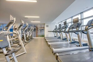 Uma academia com várias esteiras e equipamentos de ginástica, janelas amplas e um design moderno e limpo.