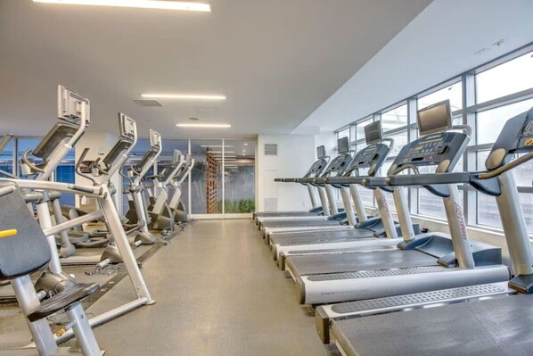 A gym with multiple treadmills and exercise equipment, large windows, and a clean, modern design.