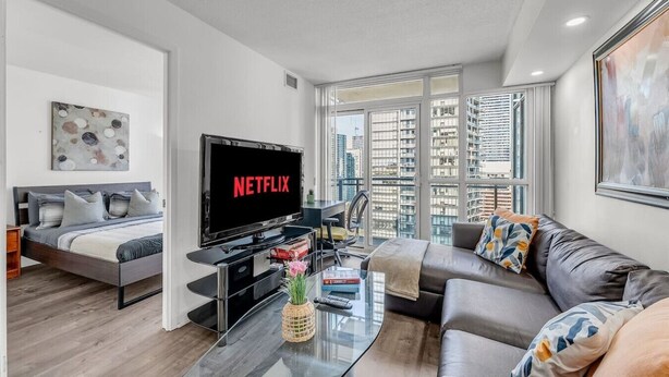 Ein modernes Wohnzimmer mit einem Bett, einem Sofa, einem Fernseher und einem Glastisch.
