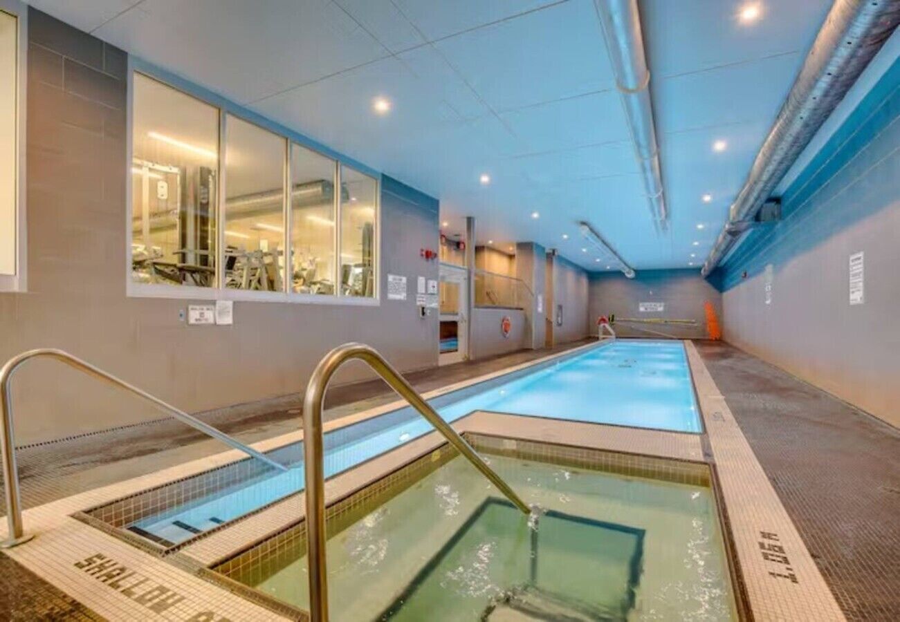 A swimming pool with a glass wall on one side, a changing room area, and a shower area.