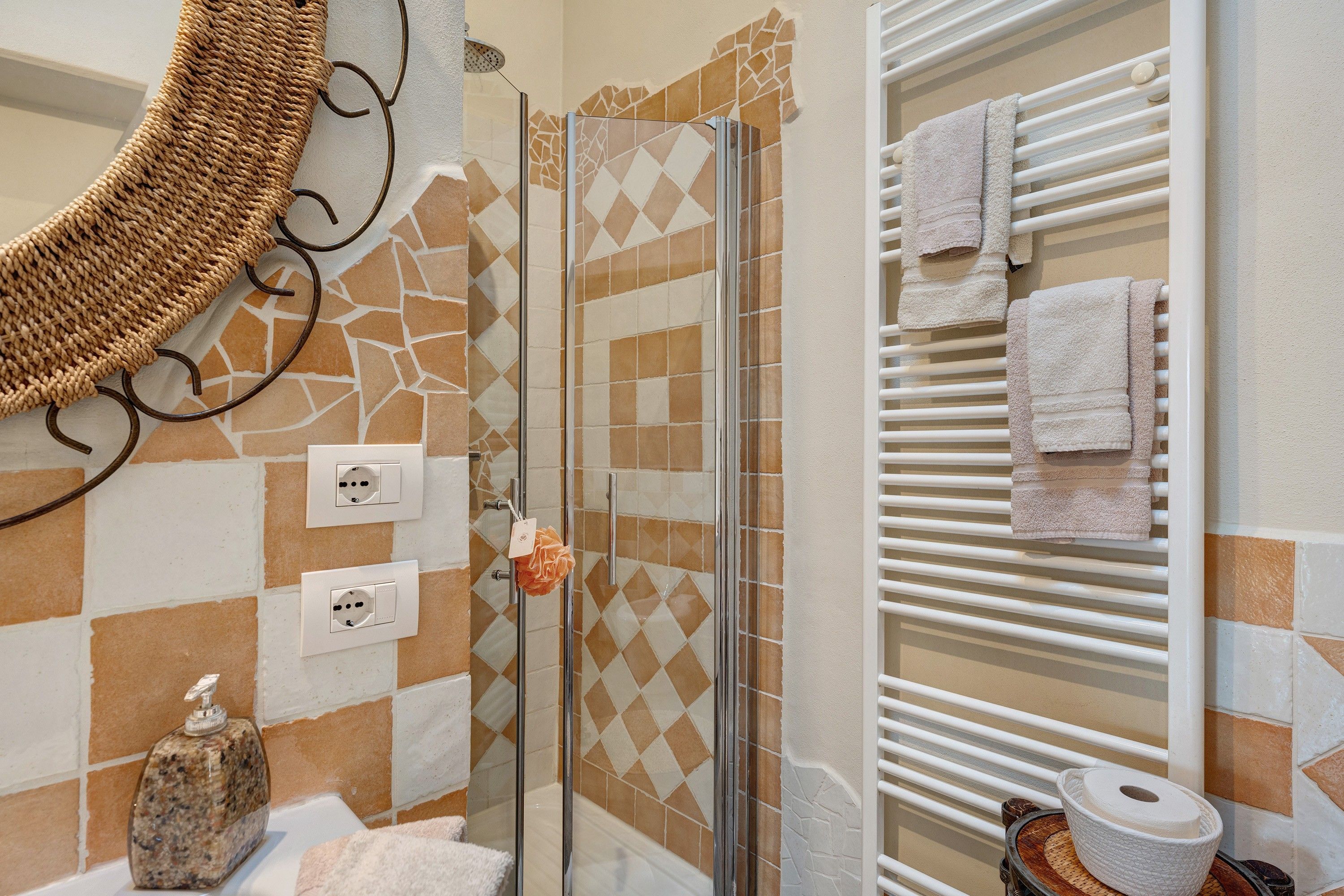 Ein Badezimmer mit Dusche, geflieste Wände, einem Handtuchhalter und einer Seifenspender.