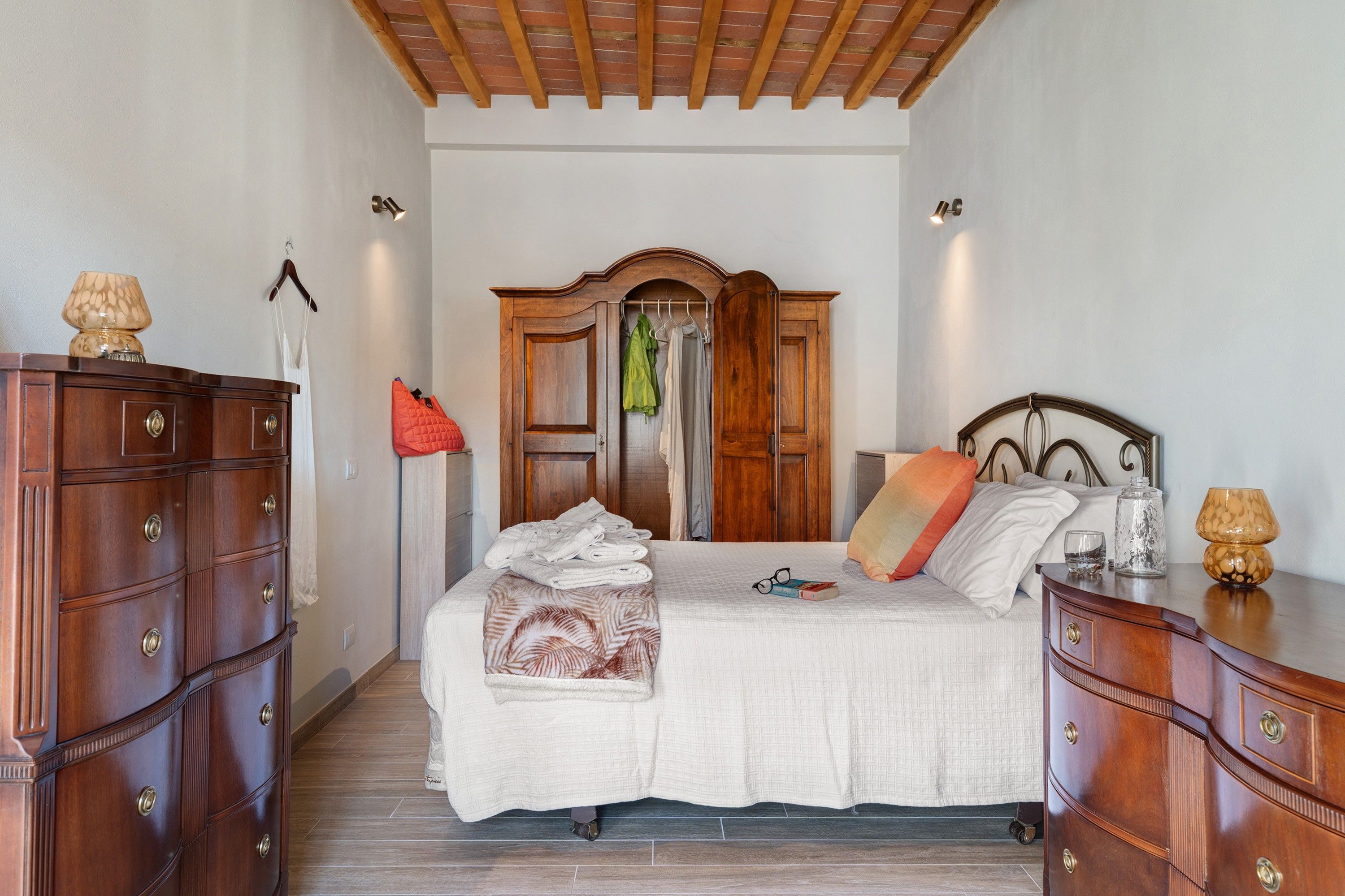 Una camera da letto con un letto, un armadio in legno, uno specchio e un appendiabiti.