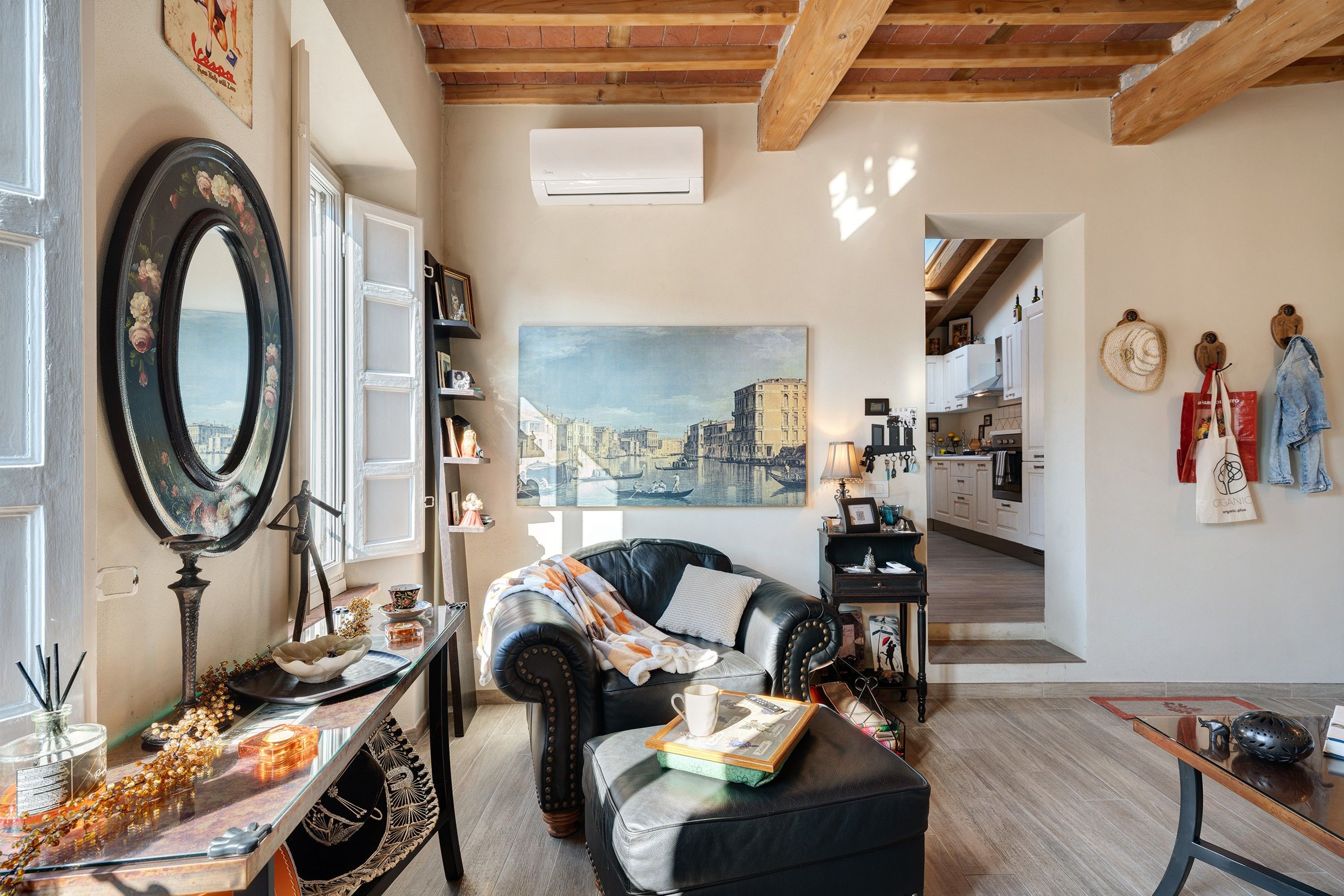 Un accogliente soggiorno con un divano in pelle, un tavolino da caffè e un quadro raffigurante un panorama urbano.