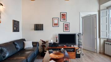 Un soggiorno con un divano in pelle, una televisione a schermo piatto, un tavolino da caffè con oggetti decorativi e quadri appesi al muro.