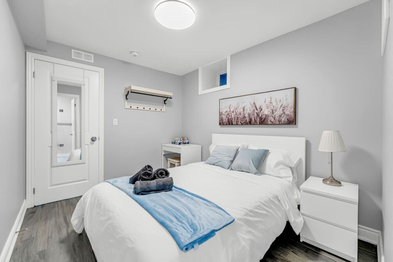 A hotel room with a bed, bedside table, and a mirror.