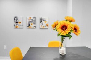 Ein Essbereich mit Tisch, Stühlen und drei an der Wand befestigten Kunstwerken.