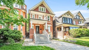 A two-story residential building with a front porch, a staircase leading to the entrance, and a well-maintained lawn. - *Minutes to BMO Field* 3BR Home in Downtown (Toronto)