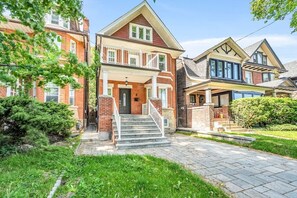 Ein zweistöckiges Wohnhaus mit Veranda, einer zur Eingangstür führenden Treppe und einem gepflegten Rasen.