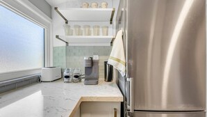 Una cocina moderna con un refrigerador de acero inoxidable, una cafetera Keurig y un tostador sobre la encimera.