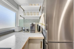 Eine moderne Küche mit einem Edelstahl-Kühlschrank, einer Keurig-Kaffeemaschine und einem Toaster auf der Arbeitsfläche.