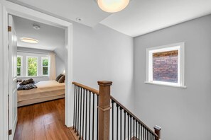 A staircase with a wooden handrail leading to a bedroom with a bed and a window. - *1 Minute to BMO Field* 4 Bedroom Home In Downtown (Toronto)