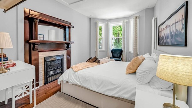 Un dormitorio con cama, chimenea, escritorio y una silla.