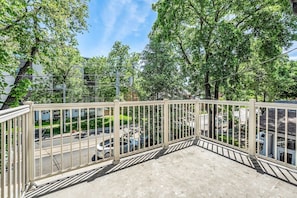 A balcony with a metal railing, a concrete floor, and a view of a street with parked cars and trees. - *1 Minute to BMO Field* 4 Bedroom Home In Downtown (Toronto)