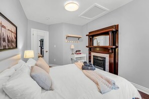 A hotel room with a bed, bedside table, lamp, and a fireplace. - *1 Minute to BMO Field* 4 Bedroom Home In Downtown (Toronto)