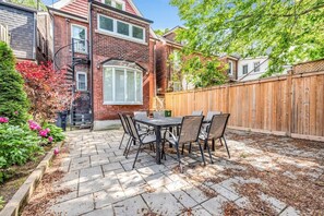 A patio with a table and chairs, surrounded by a brick wall and a wooden fence. - *1 Minute to BMO Field* 4 Bedroom Home In Downtown (Toronto)