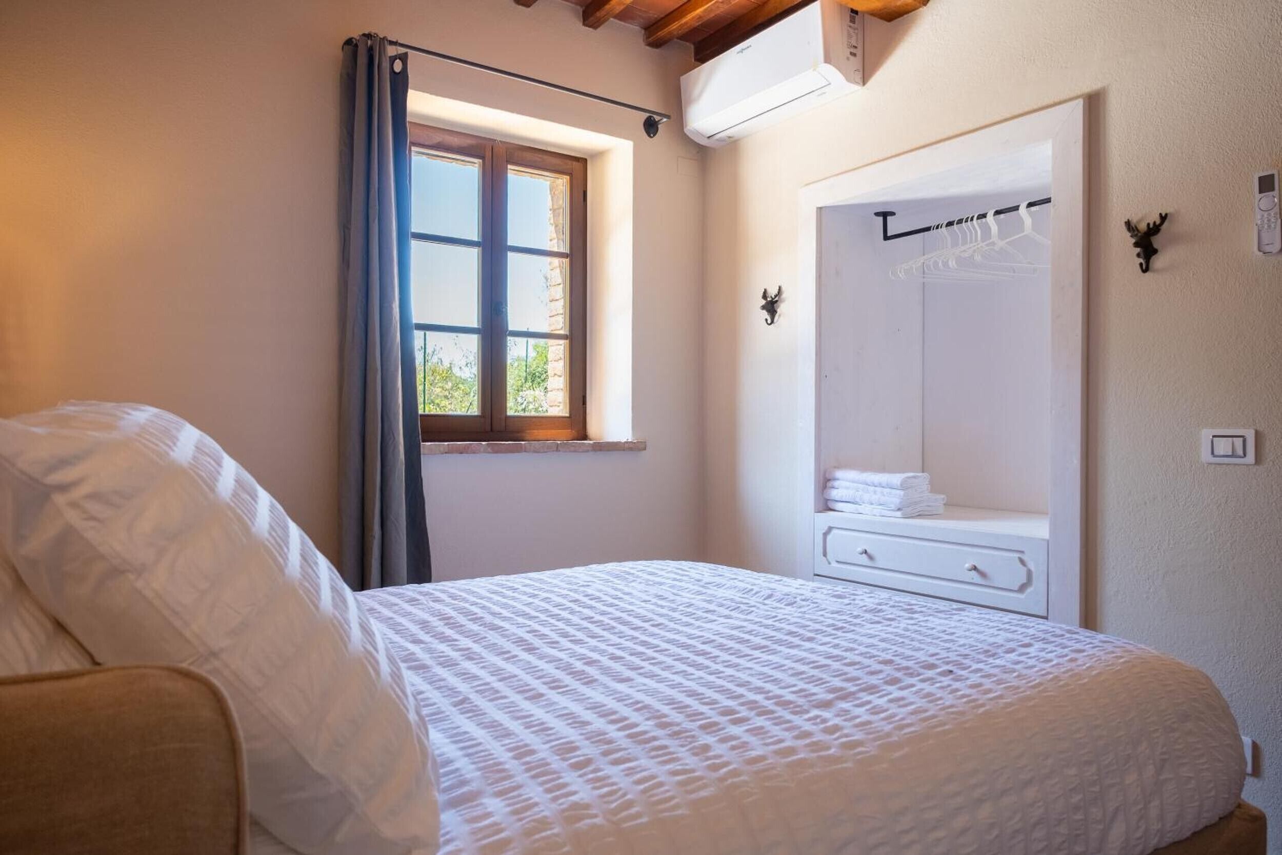 A bedroom with a bed, a window with curtains, a wardrobe, and a mirror.
