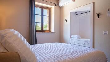 A bedroom with a bed, a window with curtains, a wardrobe, and a mirror.