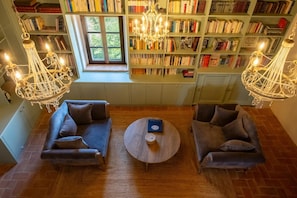 A cozy reading room with two sofas, a round coffee table, and a large bookshelf filled with books. - Villa San Biagio – Luxury villa, newly renovated villa with Pool, stunning views, pool & airco (Città della Pieve)