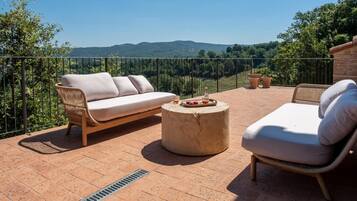 A terrace with a sofa, a chair, and a round table with fruit.