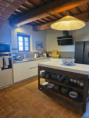 A kitchen with a central island, a hanging light fixture, a window, and a mounted television. - Villa San Biagio – Luxury villa, newly renovated villa with Pool, stunning views, pool & airco (Città della Pieve)