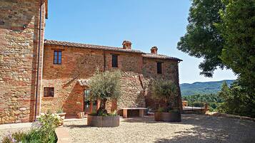 A stone building with a courtyard, outdoor seating, and a view of the hills.