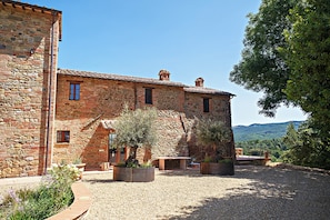 Un edifici de pedra amb un pati interior, espais d'exterior per seure i vistes a les colines.