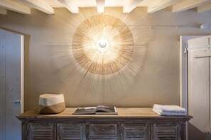 Un baño con tocador de madera, pared con textura y lámpara de techo circular.