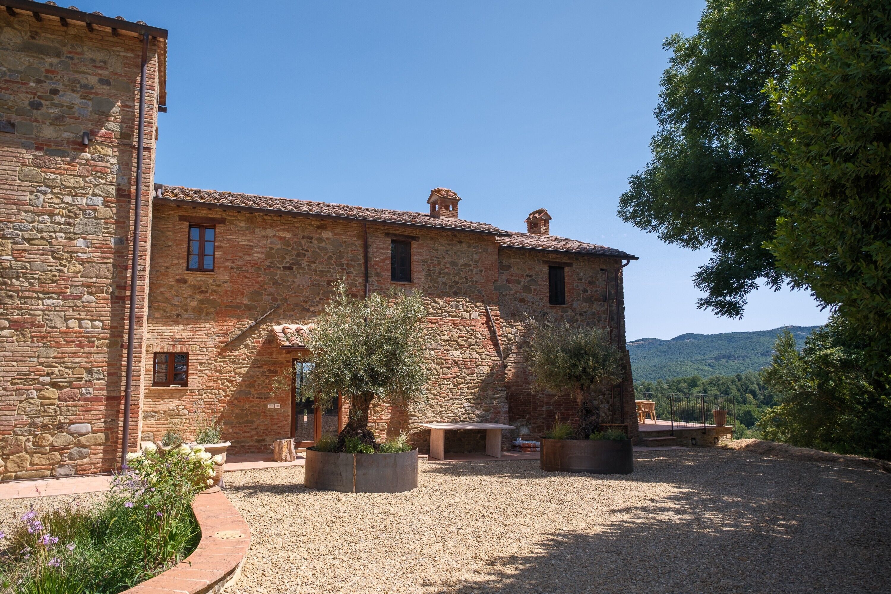 A stone building with a courtyard, outdoor seating, and a view of the surrounding landscape.