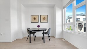 A dining area with a round table, four chairs, and two framed artworks on the wall.
