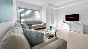 A modern living room with a sofa, coffee table, and a television displaying 'NETFLIX'.