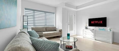 A modern living room with a sofa, coffee table, and a television displaying 'NETFLIX'.