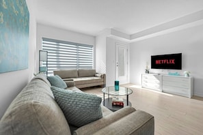 A modern living room with a sofa, coffee table, and a television displaying 'NETFLIX'.